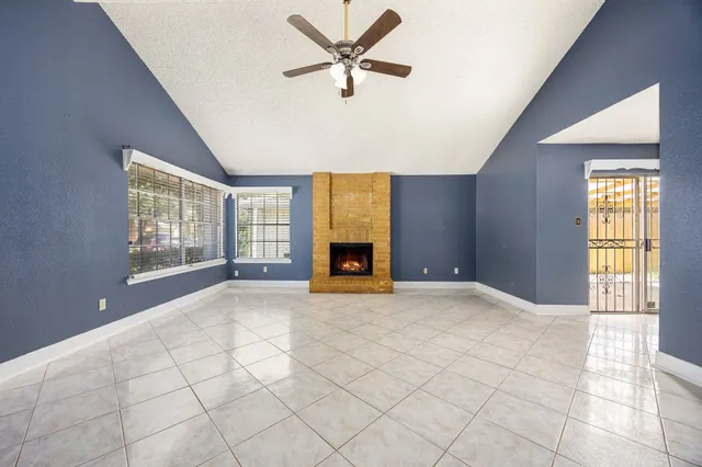 a view of an empty room with a window and kitchen view