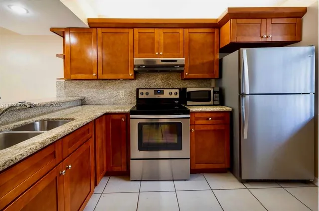 a kitchen with stainless steel appliances granite countertop a refrigerator stove and sink