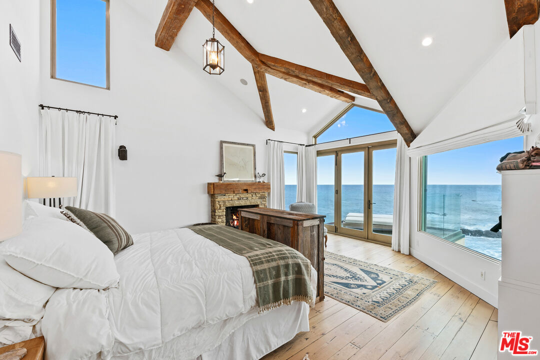 24920 Malibu Road Malibu, CA 90265 - Photo 18 of 49 a bedroom with a bed a table and large windows