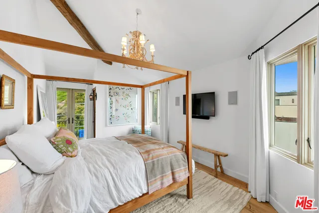 a bedroom with a bed a flat screen tv and a window