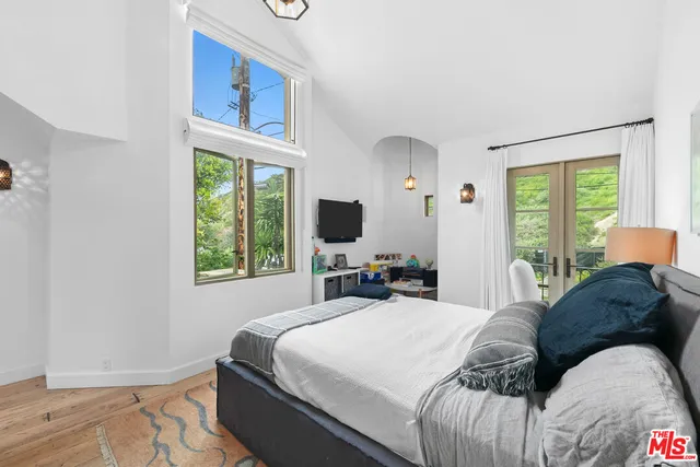 a bedroom with a bed a flat screen tv and a window