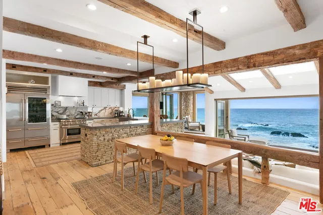 a dining hall with stainless steel appliances kitchen island granite countertop a table chairs and a view of living room