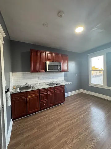 a large kitchen with stainless steel appliances granite countertop a stove a sink and a granite counter tops with wooden floors