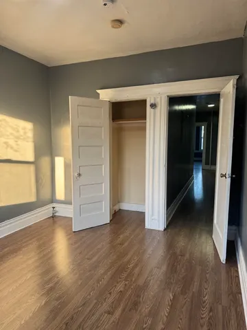 an empty room with wooden floor closet and windows