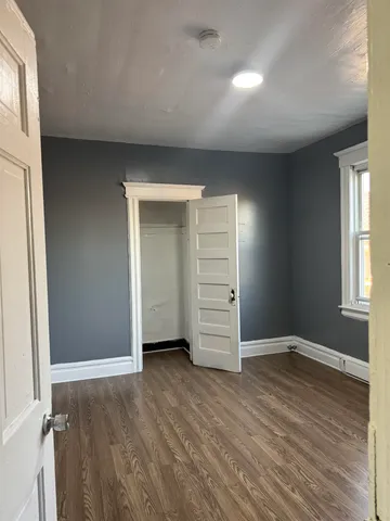 an empty room with wooden floor closet and windows