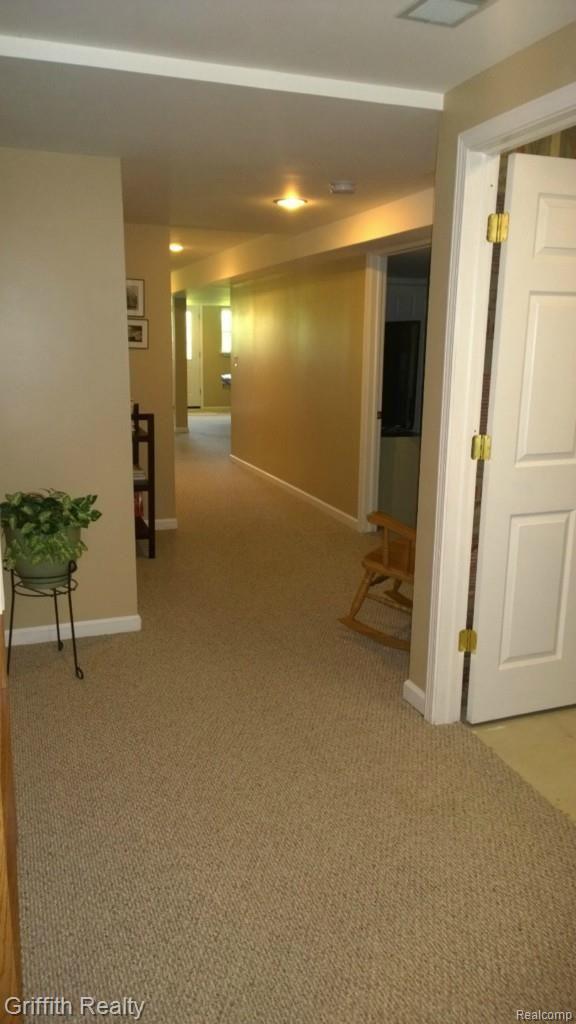 736 Fowlerville Road Fowlerville, MI 48836 - Photo 42 of 84 View in finished LL at bottom of stairs...neutral tones and carpets. first door on rite is the mechanical room. 2nd is the guest room/office. in the background is the family room