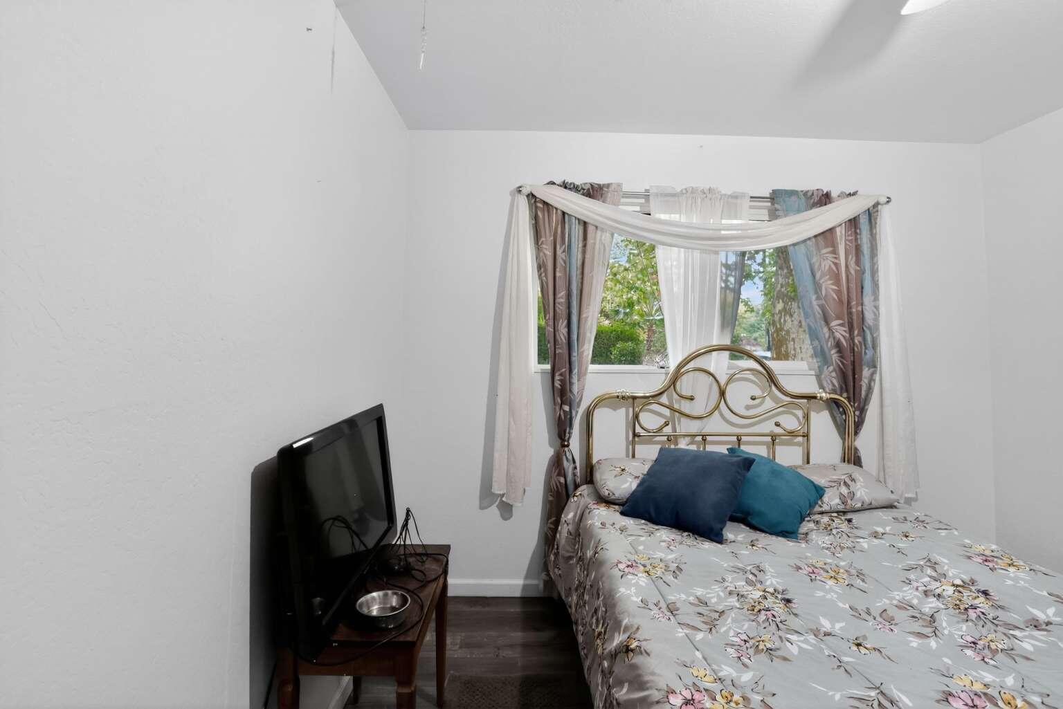 7408 Bridge Lane Redding, CA 96002 - Photo 21 of 25 a bedroom with a bed and a flat tv screen on dresser