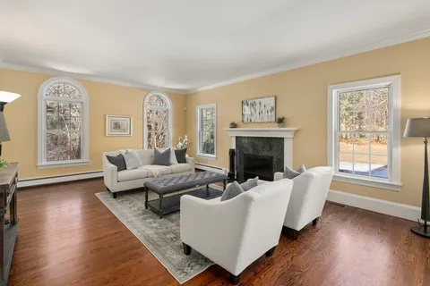 a living room with furniture large window and wooden floor
