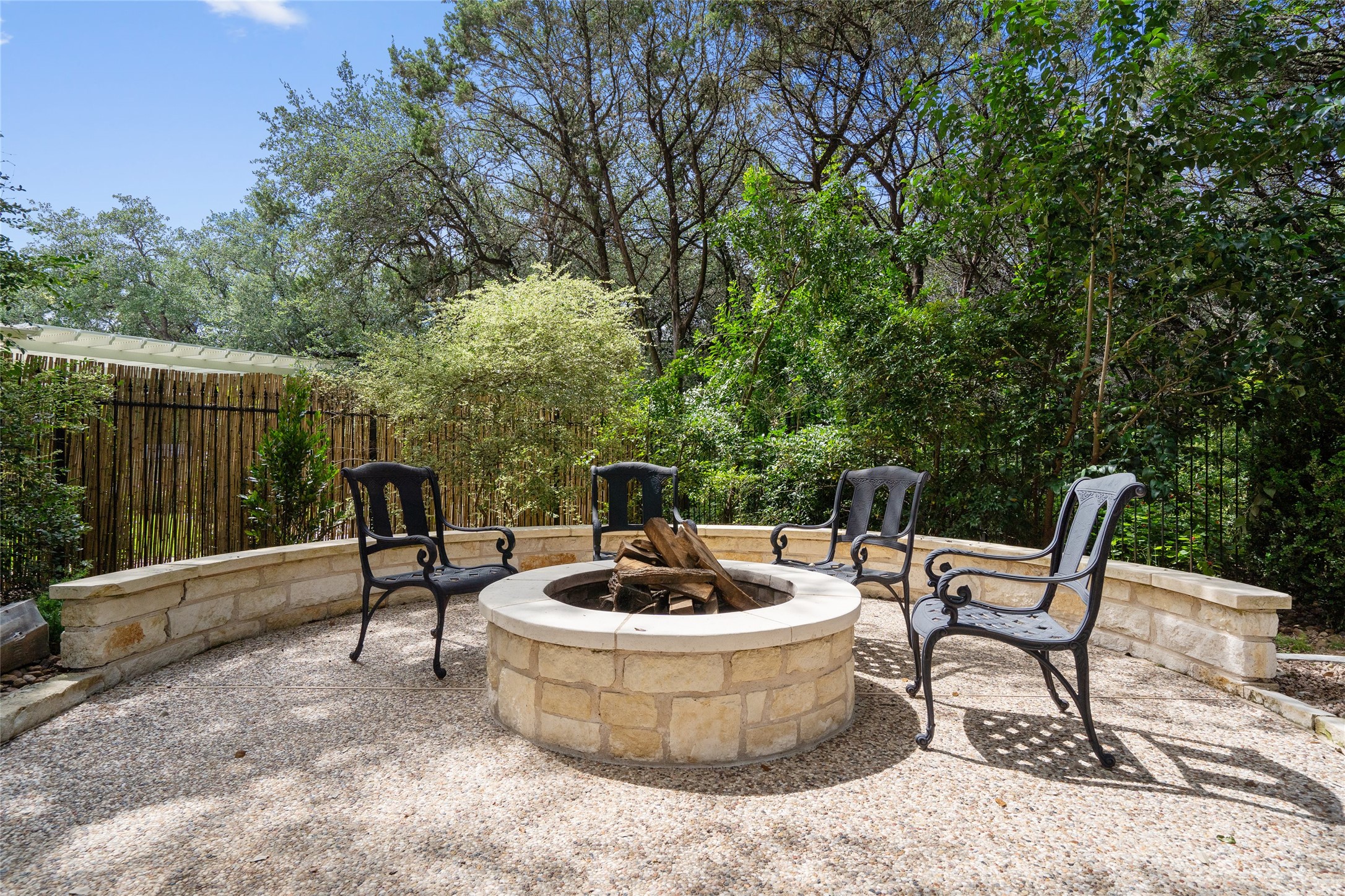 4313 Rio Robles Drive Austin, TX 78746 - Photo 37 of 40 A private backyard retreat featuring a stone fire pit and mature landscaping.