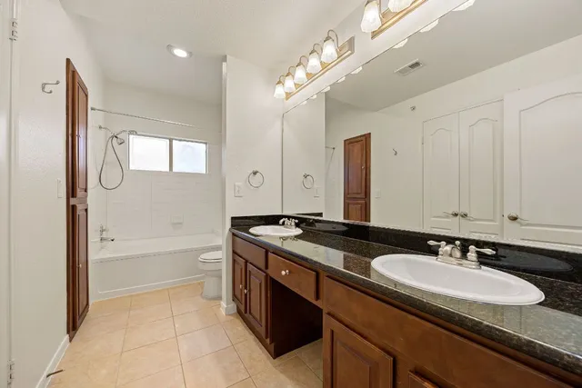 a bathroom with a granite countertop sink a mirror a bathtub and shower