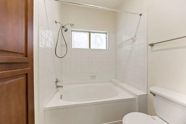 a white bath tub sitting next to a white toilet and a shower