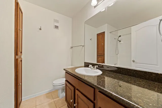 a bathroom with a granite countertop sink a toilet and a mirror