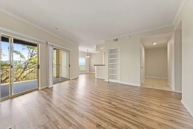 a view of an empty room with a window and wooden floor