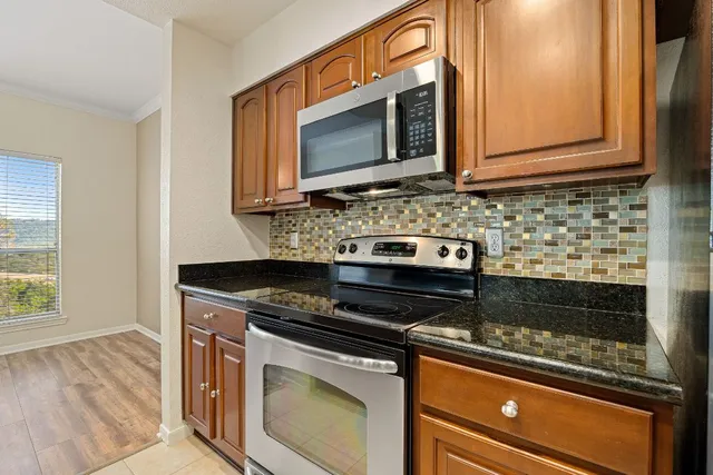 a kitchen with granite countertop a stove and a microwave