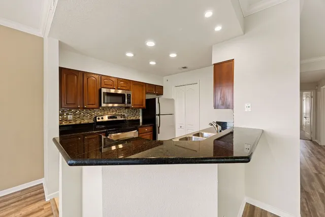 a kitchen with stainless steel appliances granite countertop a sink and a refrigerator