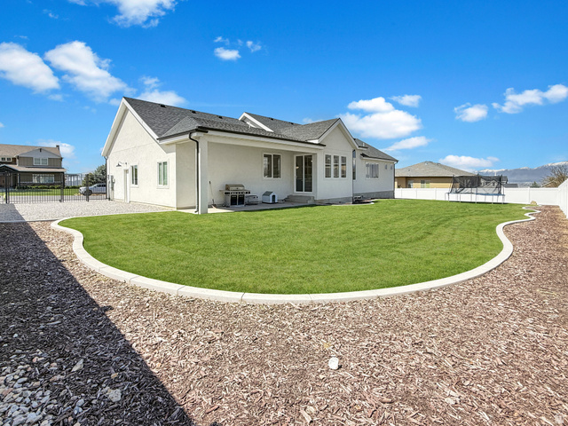 916 Rocky Mountain Way Elk Ridge, UT 84651 - Photo 50 of 54 Back of house with a fenced backyard, a patio, stucco siding, a trampoline, and roof with shingles