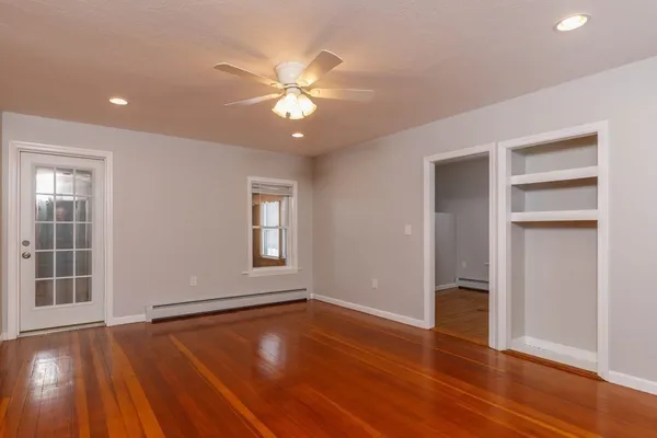 a view of an empty room with wooden floor and a window