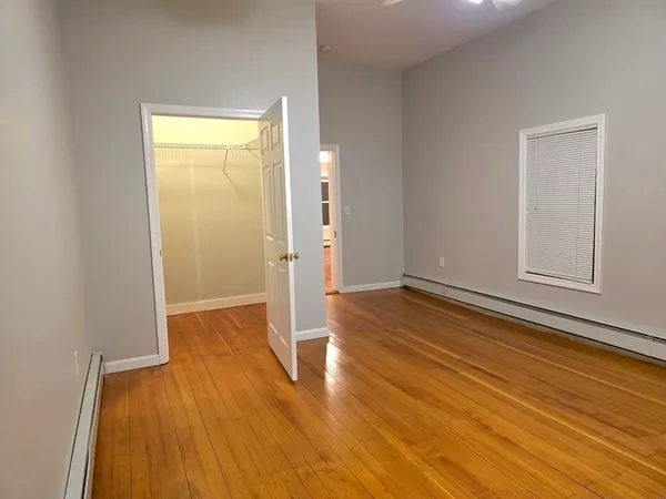 a view of an empty room with window and wooden floor
