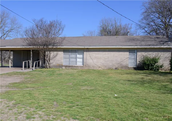a front view of house with yard and trees in the background