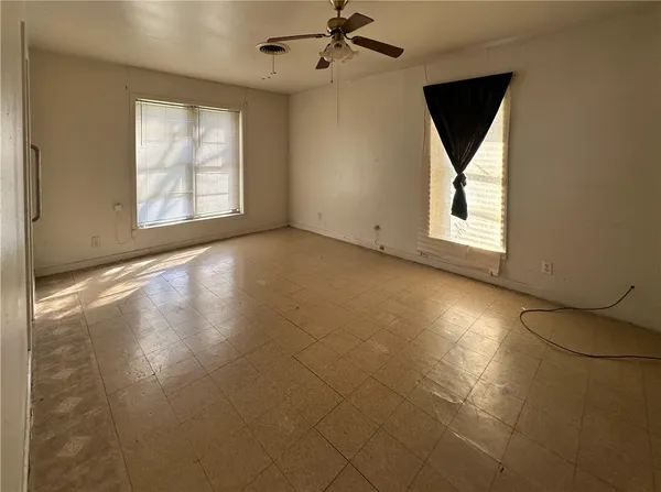 an empty room with windows and fan