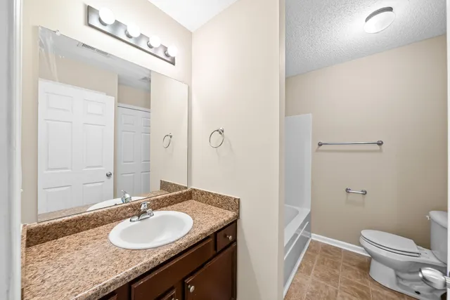 a bathroom with a granite countertop sink toilet and a mirror