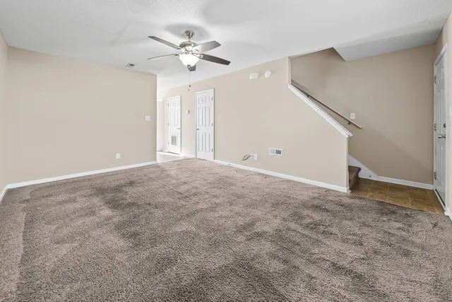 a view of an empty room with a chandelier fan
