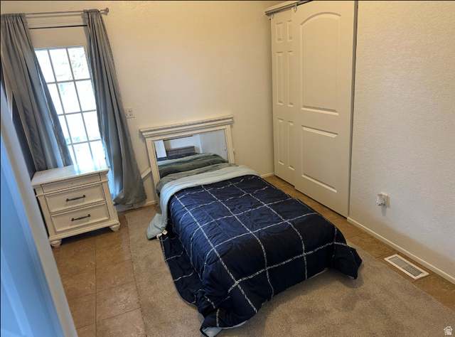 265 Mindella Way Layton, UT 84041 - Photo 27 of 32 Bedroom space featuring a multi-pane window, tile flooring, and a sliding barn-door style closet