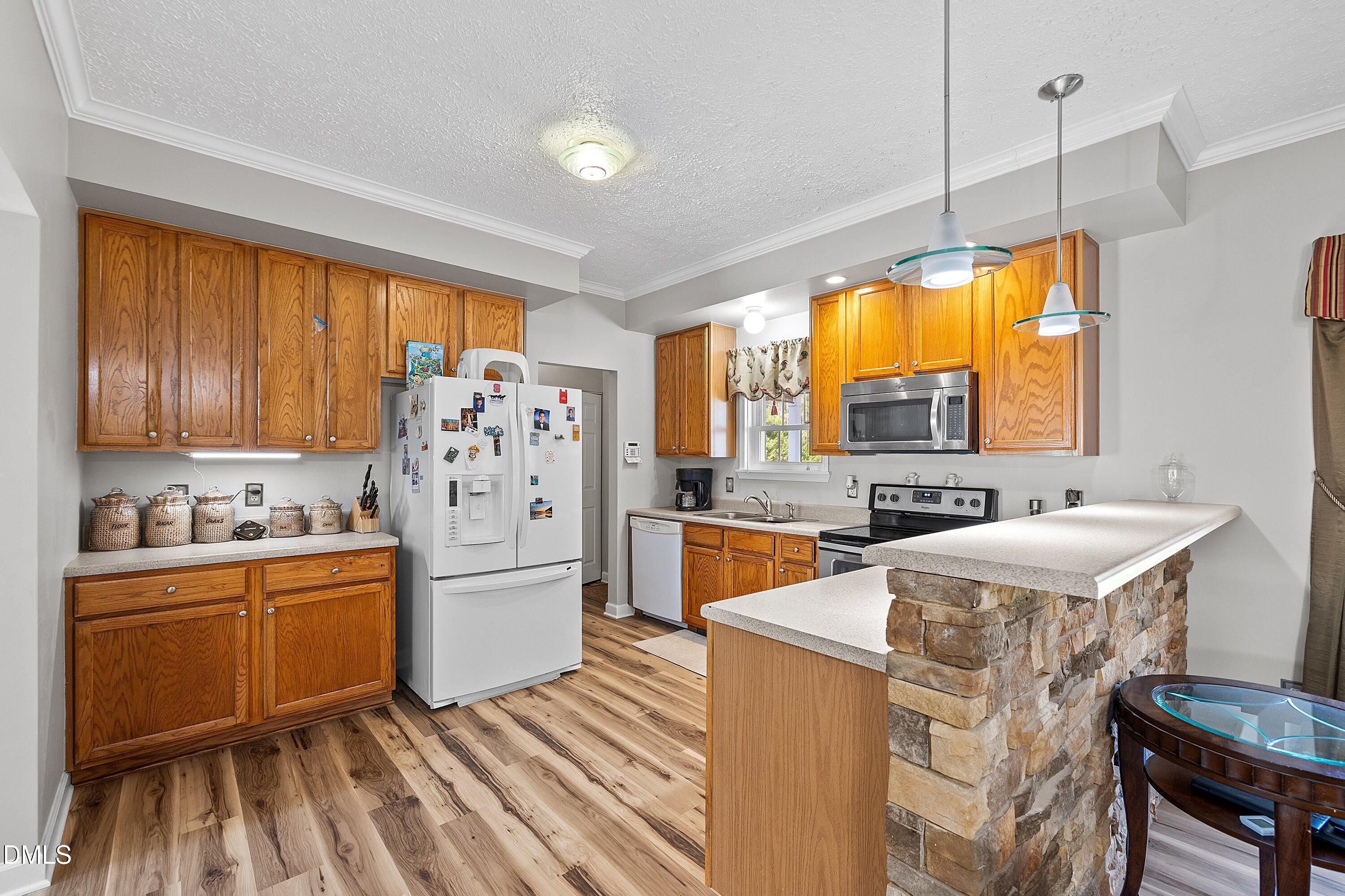 2265 Bud Lipscomb Road Willow Spring, NC 27592 - Photo 16 of 76 a kitchen with stainless steel appliances granite countertop a refrigerator a sink dishwasher a stove and white countertops with wooden floor