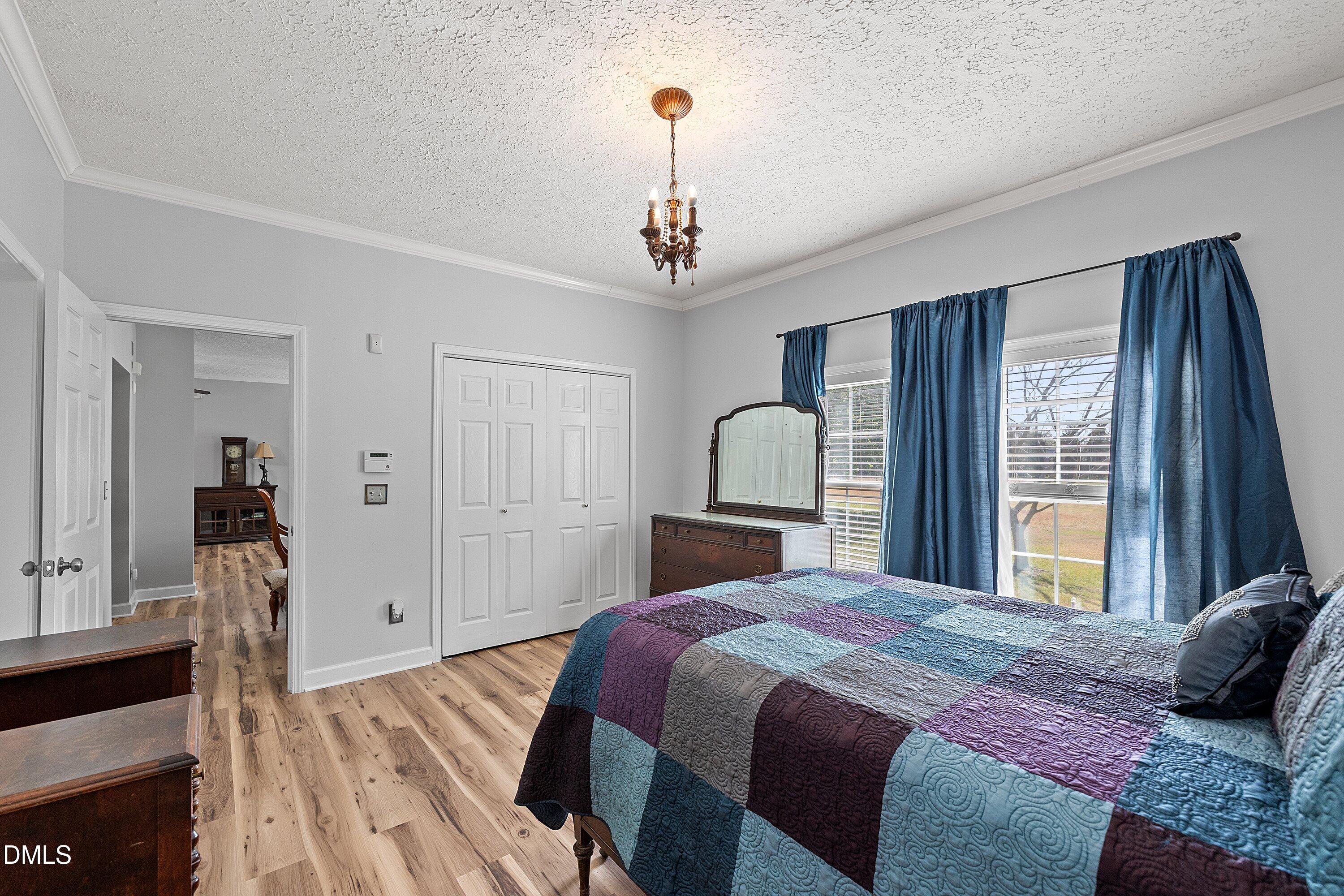 2265 Bud Lipscomb Road Willow Spring, NC 27592 - Photo 24 of 76 a bedroom with a bed wooden floor and a chandelier