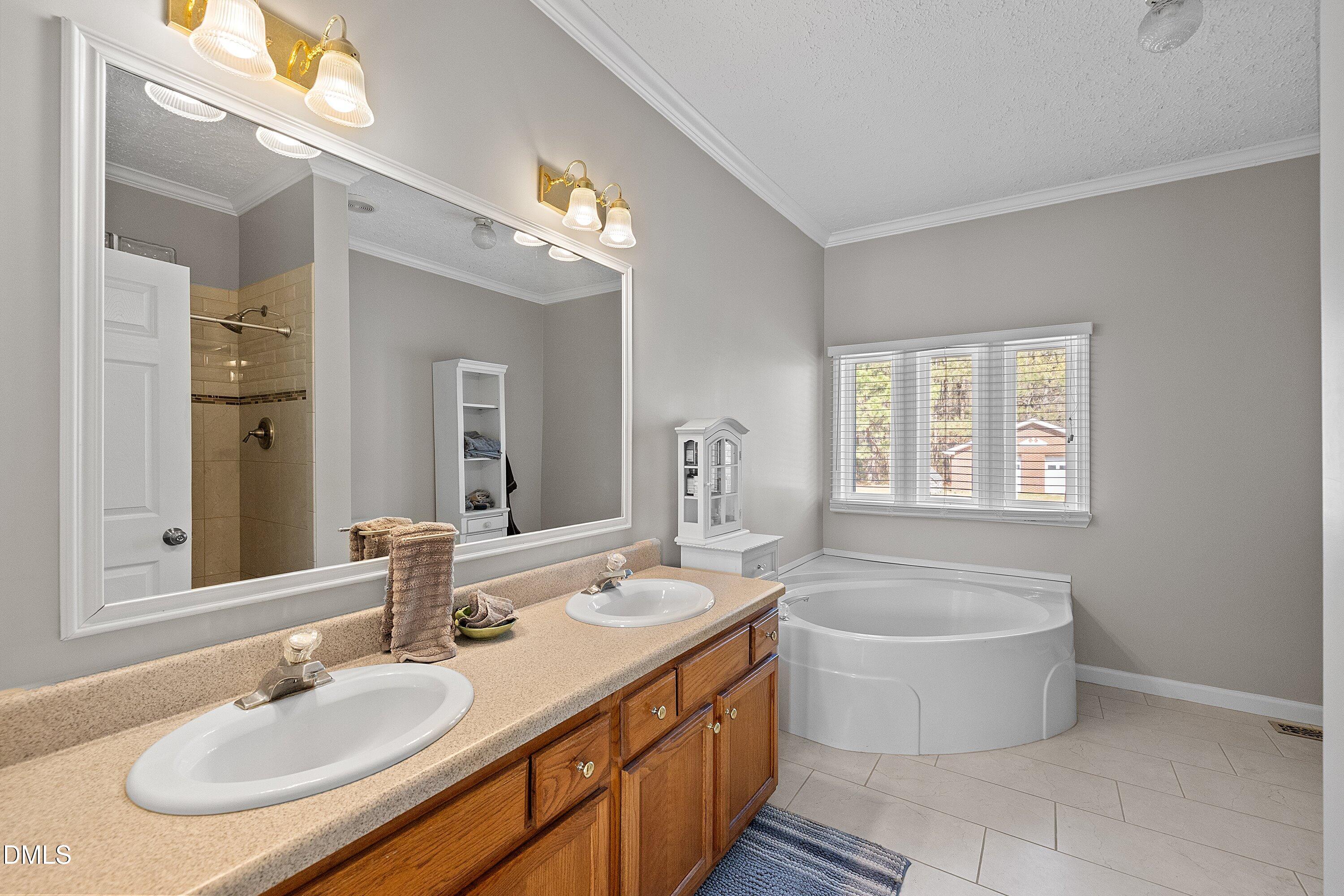 2265 Bud Lipscomb Road Willow Spring, NC 27592 - Photo 25 of 76 a bathroom with a tub a double vanity sink and a mirror