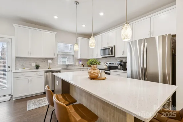 a kitchen with a refrigerator a stove a sink and white cabinets with wooden floor