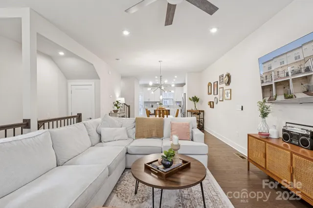a living room with furniture kitchen view and a wooden floor