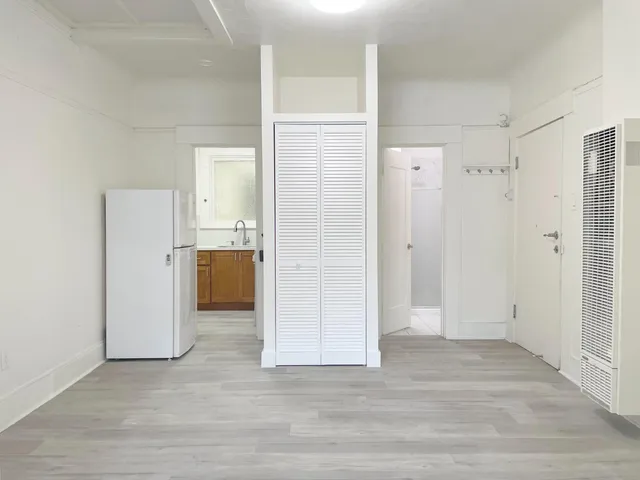 a view of a kitchen with a refrigerator and wooden cabinets