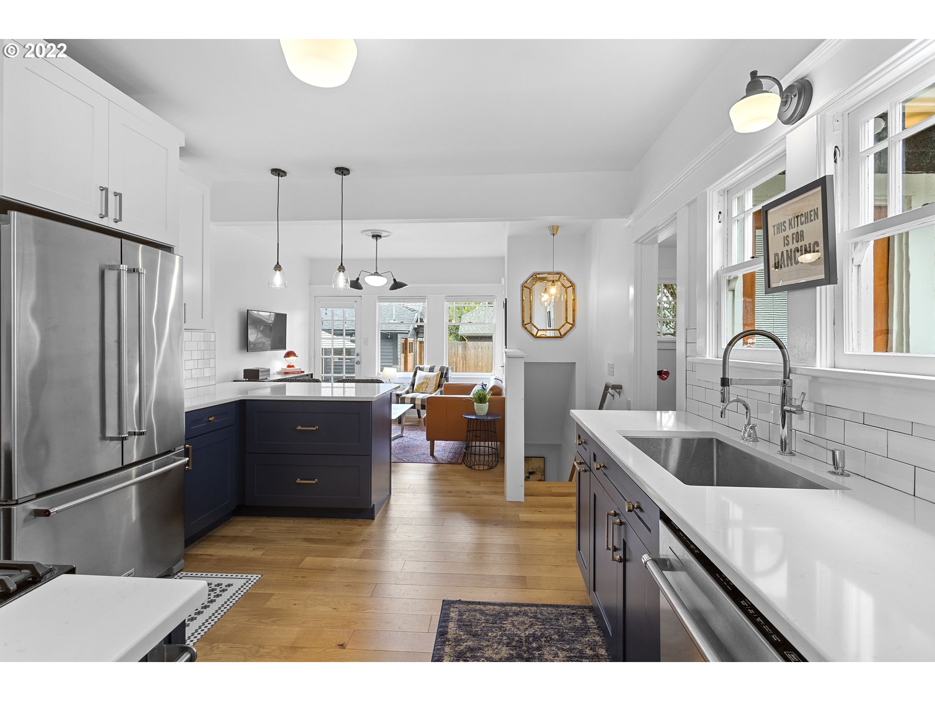 6429 North Commercial Avenue Portland, OR 97217 - Photo 7 of 32 a kitchen with stainless steel appliances kitchen island granite countertop a refrigerator a sink dishwasher and white cabinets with wooden floor