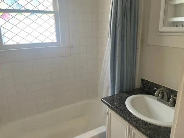 a bathroom with a granite countertop sink and a bathtub