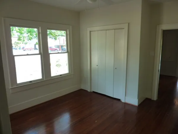 an empty room with wooden floor and windows