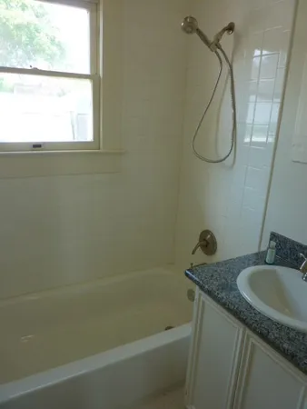 a bathroom with a granite countertop sink a mirror a vanity and a bathtub