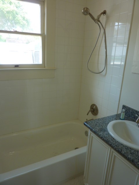 4105 McKinney Street, Unit B Houston, TX 77023 - Photo 23 of 25 a bathroom with a granite countertop sink a mirror a vanity and a bathtub