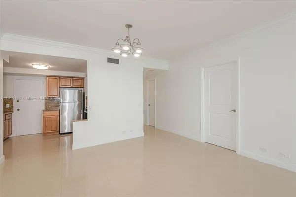 an empty room with kitchen and chandelier fan