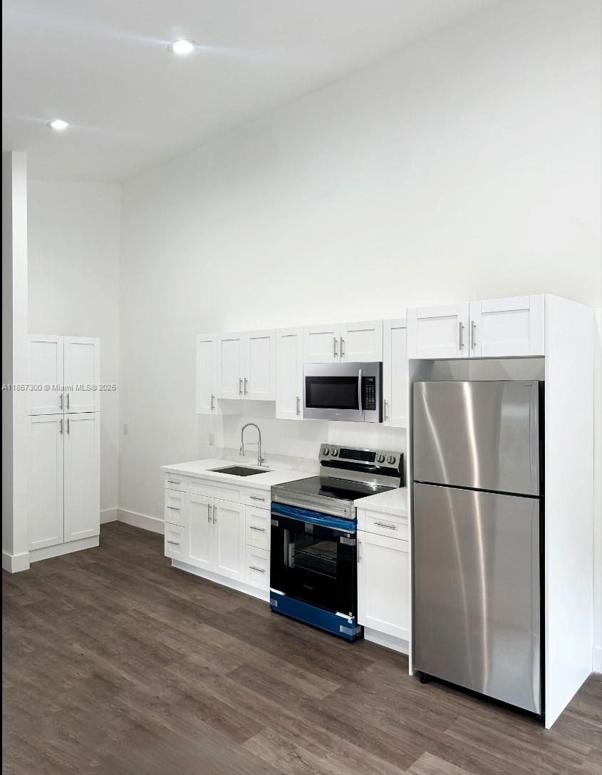 a kitchen with cabinets stainless steel appliances and wooden floor