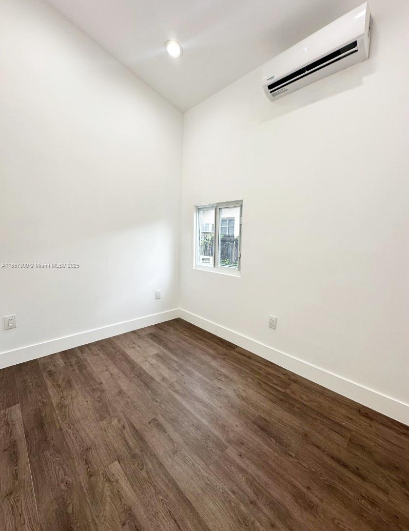 2126 Northwest 24th Street, Unit A Miami, FL 33142 - Photo 2 of 4 an empty room with wooden floor and windows