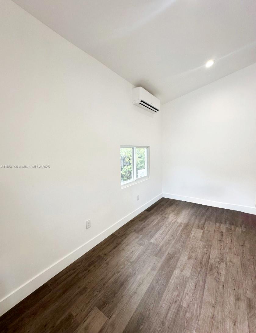 2126 Northwest 24th Street, Unit A Miami, FL 33142 - Photo 3 of 4 an empty room with wooden floor and windows