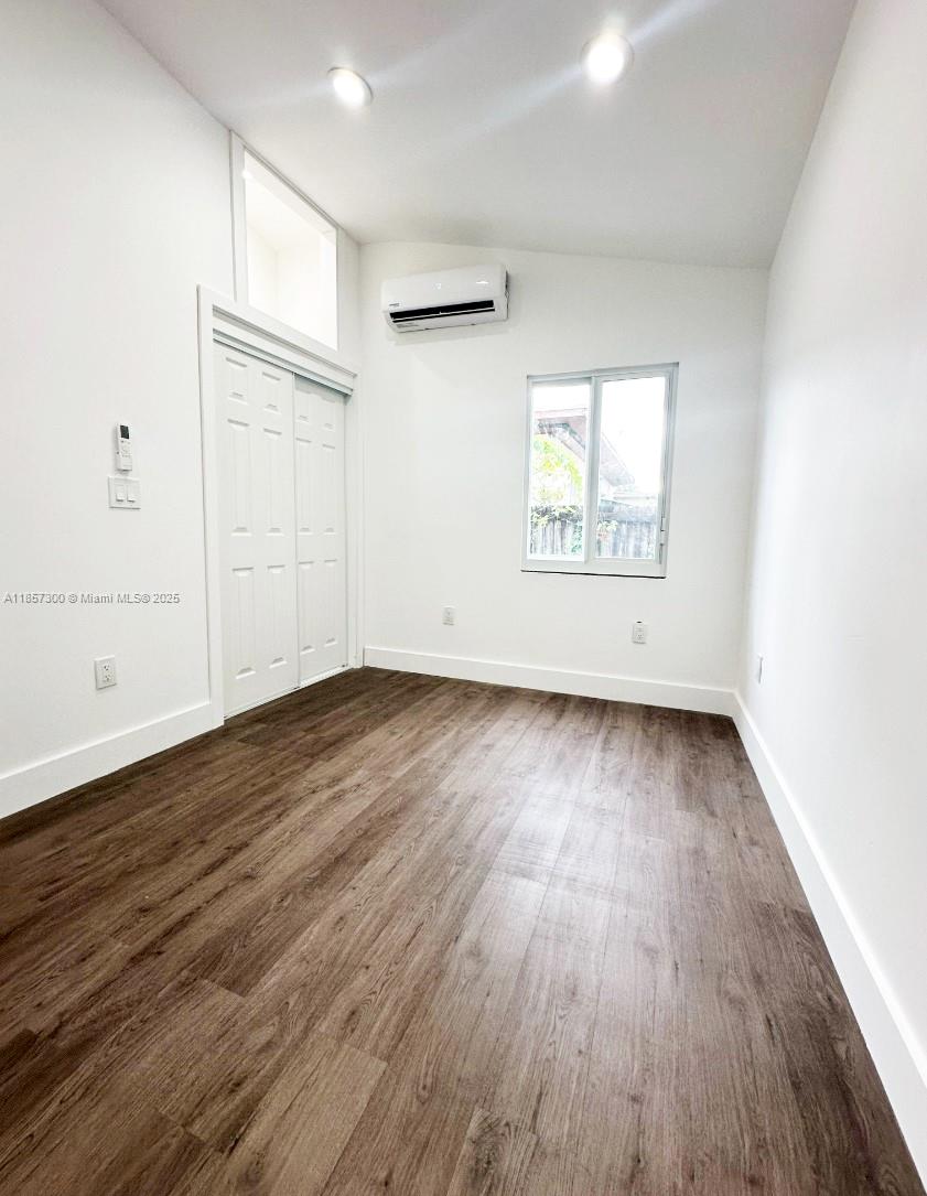2126 Northwest 24th Street, Unit A Miami, FL 33142 - Photo 4 of 4 an empty room with wooden floor and windows