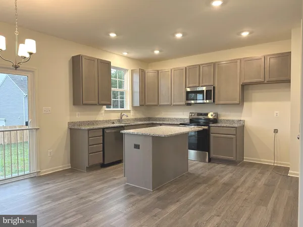 a kitchen with kitchen island granite countertop wooden floors white cabinets and stainless steel appliances