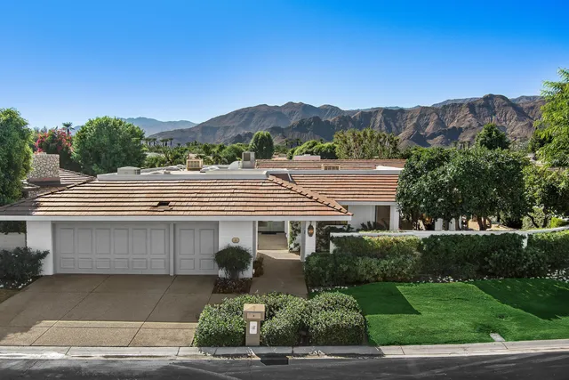 a front view of a house with a yard and mountain view