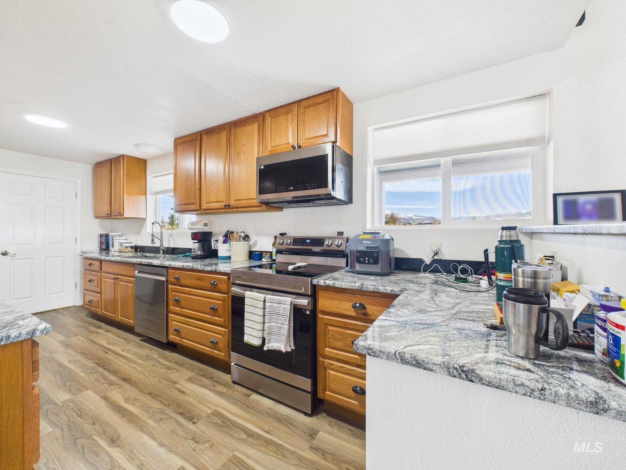 1086 Highland Lane Mesa, ID 83643 - Photo 7 of 45 Kitchen with wood finish cabinets, stainless steel appliances, light stone counters, and light wood-style flooring
