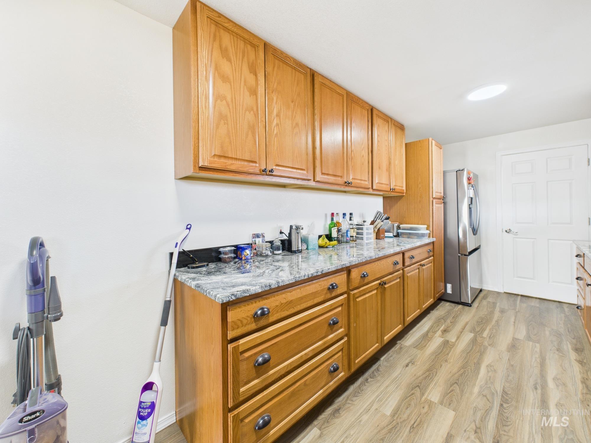 1086 Highland Lane Mesa, ID 83643 - Photo 8 of 45 Kitchen with light wood finished floors, light stone countertops, stainless steel fridge with ice dispenser, and wood finish cabinets
