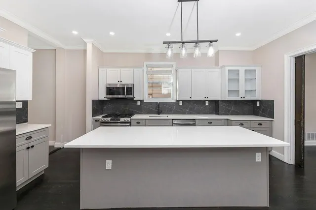 a kitchen with a sink a center island stainless steel appliances and cabinets