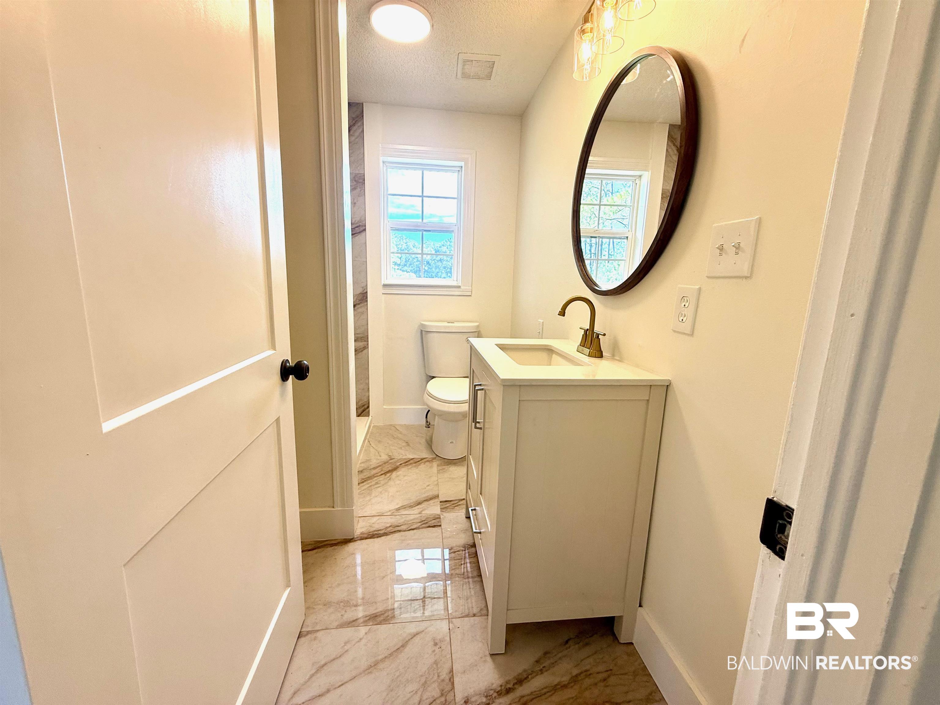 11698 Poser Road Foley, AL 36535 - Photo 10 of 20 Full bath with light marble finish flooring, vanity, a textured ceiling, and a shower