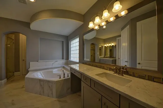 a spacious bathroom with a granite countertop sink a large mirror and a shower